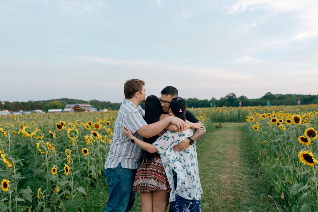 friends hugging in sunflower field at burnside farms virginia
