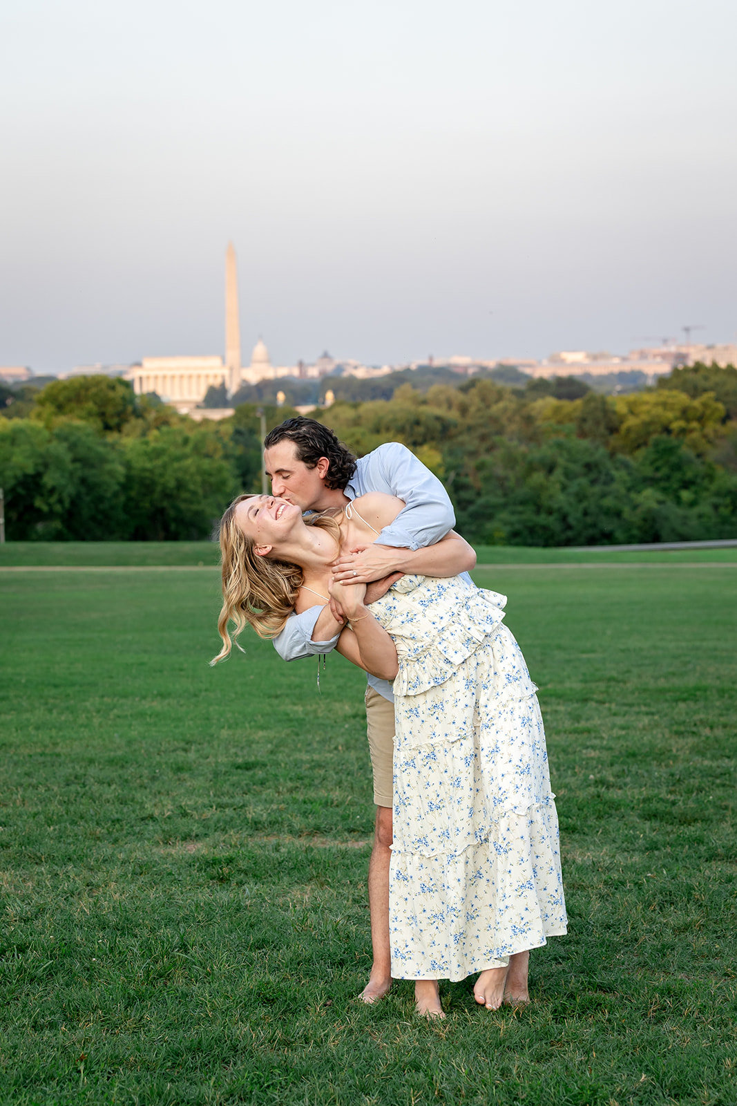 couple hugging and cheek kiss in front of DC monuments after surprise proposal